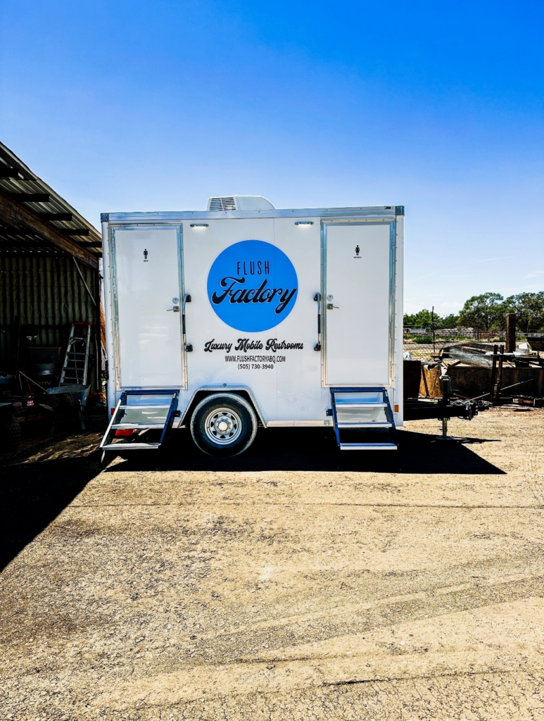 Rear view of a Flush Factory restroom trailer at a ranch