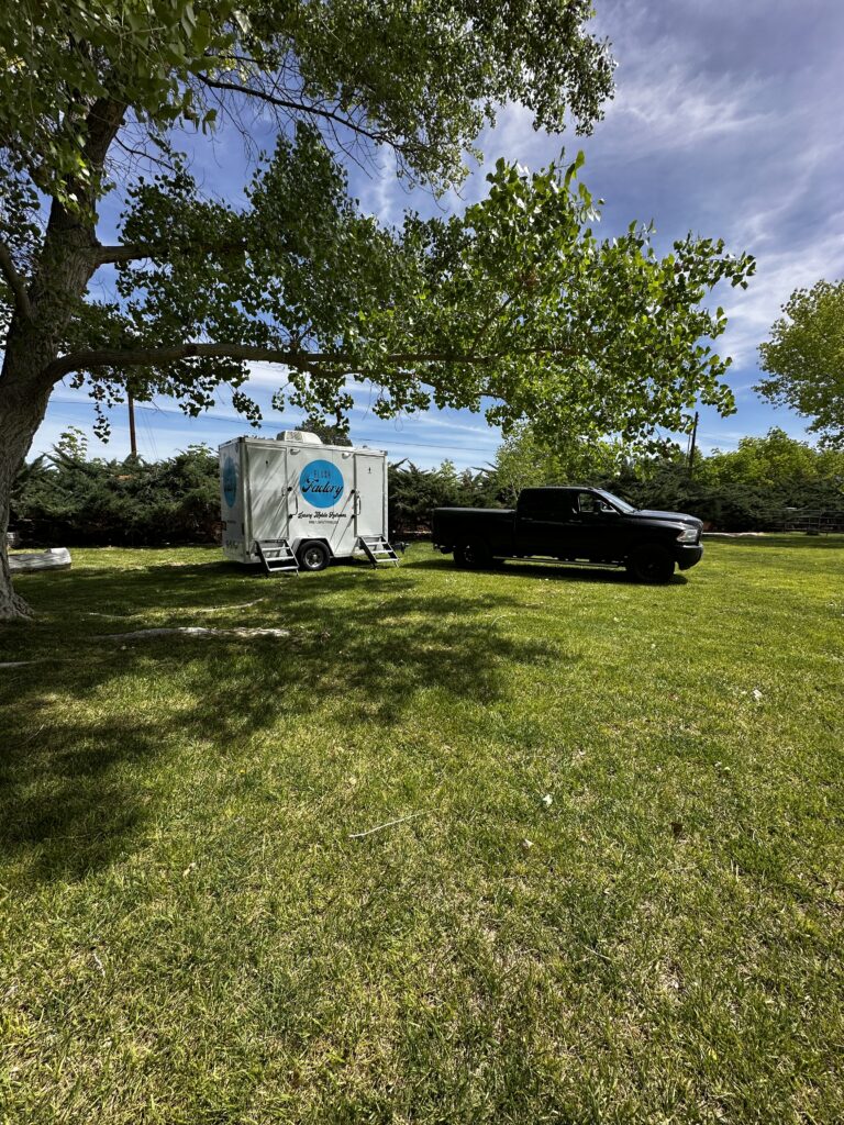 Restroom trailer on a grassy lawn at an outdoor event