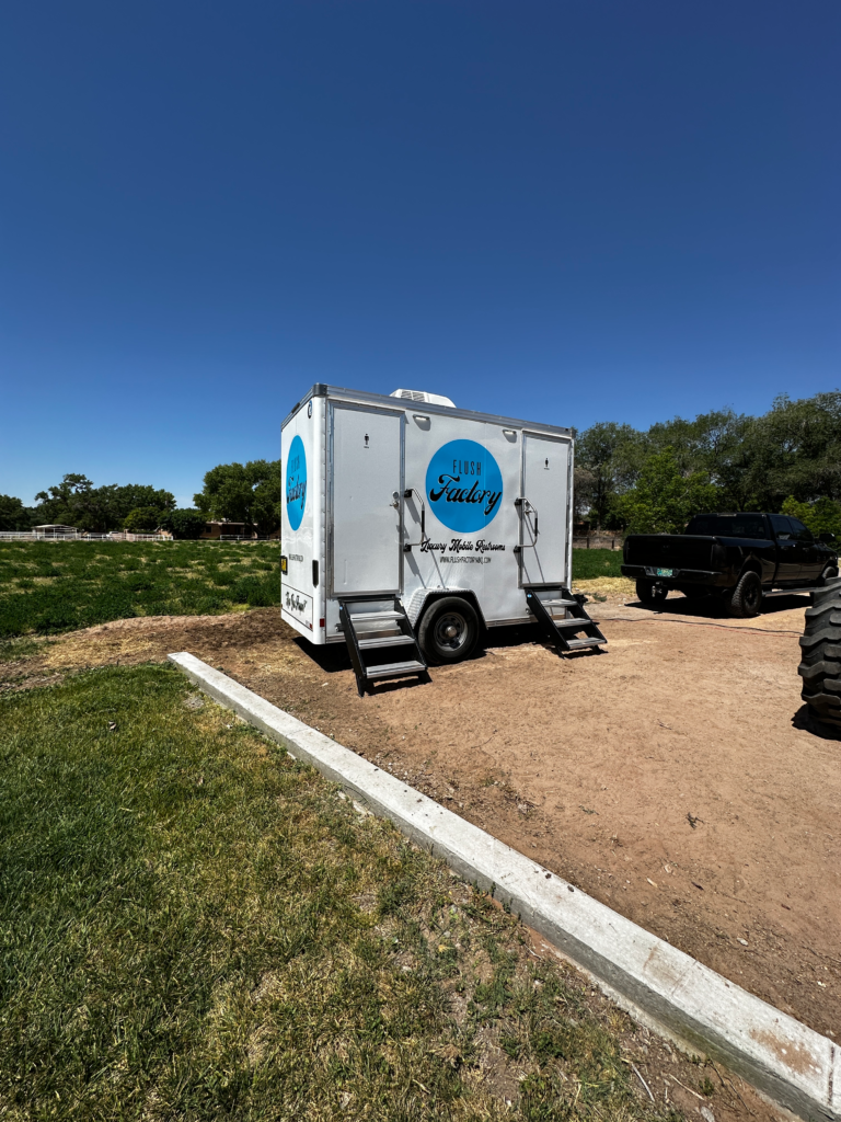 Restroom trailer placed on a gravel pad next to a lawn event