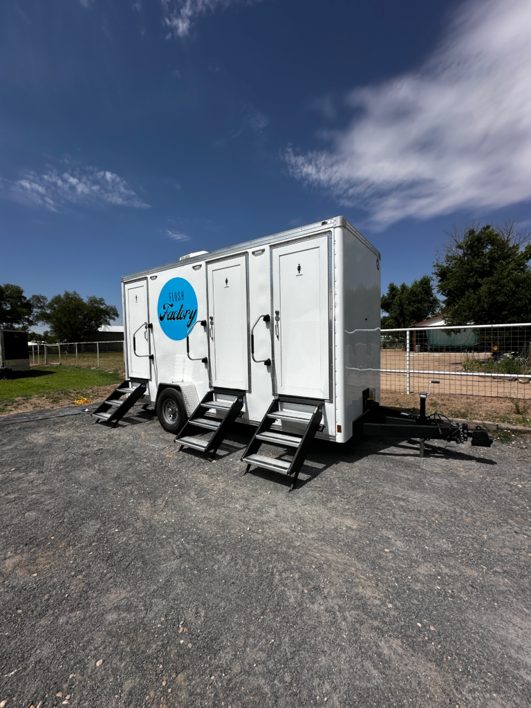 Three-stall restroom trailer set up on asphalt for a corporate event