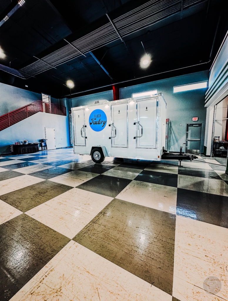 Restroom trailer set up inside an event venue with a checkered floor