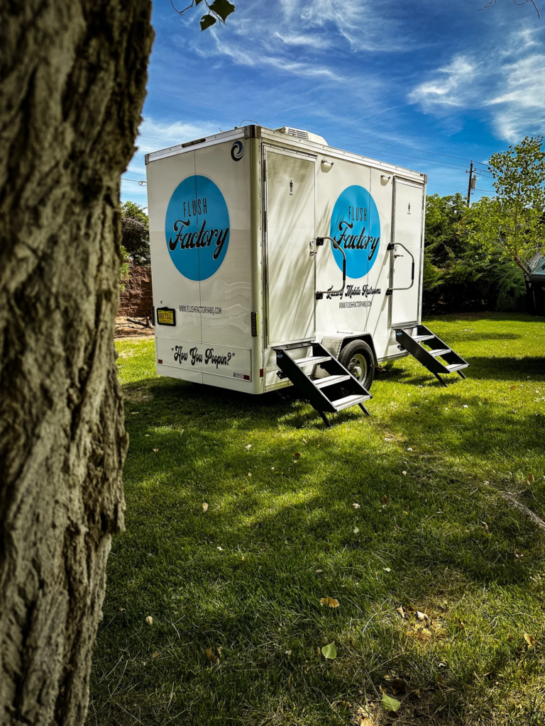 Restroom trailer set up on grass for a backyard event