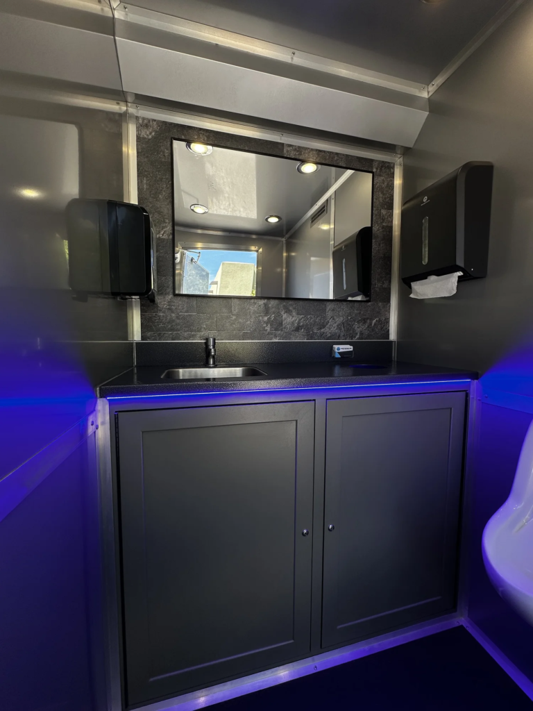 Restroom trailer vanity with sink, mirror and blue accent lighting